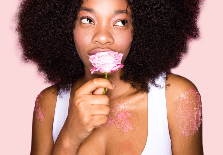 imagem de mulher com rosa na mão e usando o esfoliante rose sugar scrub no corpo
